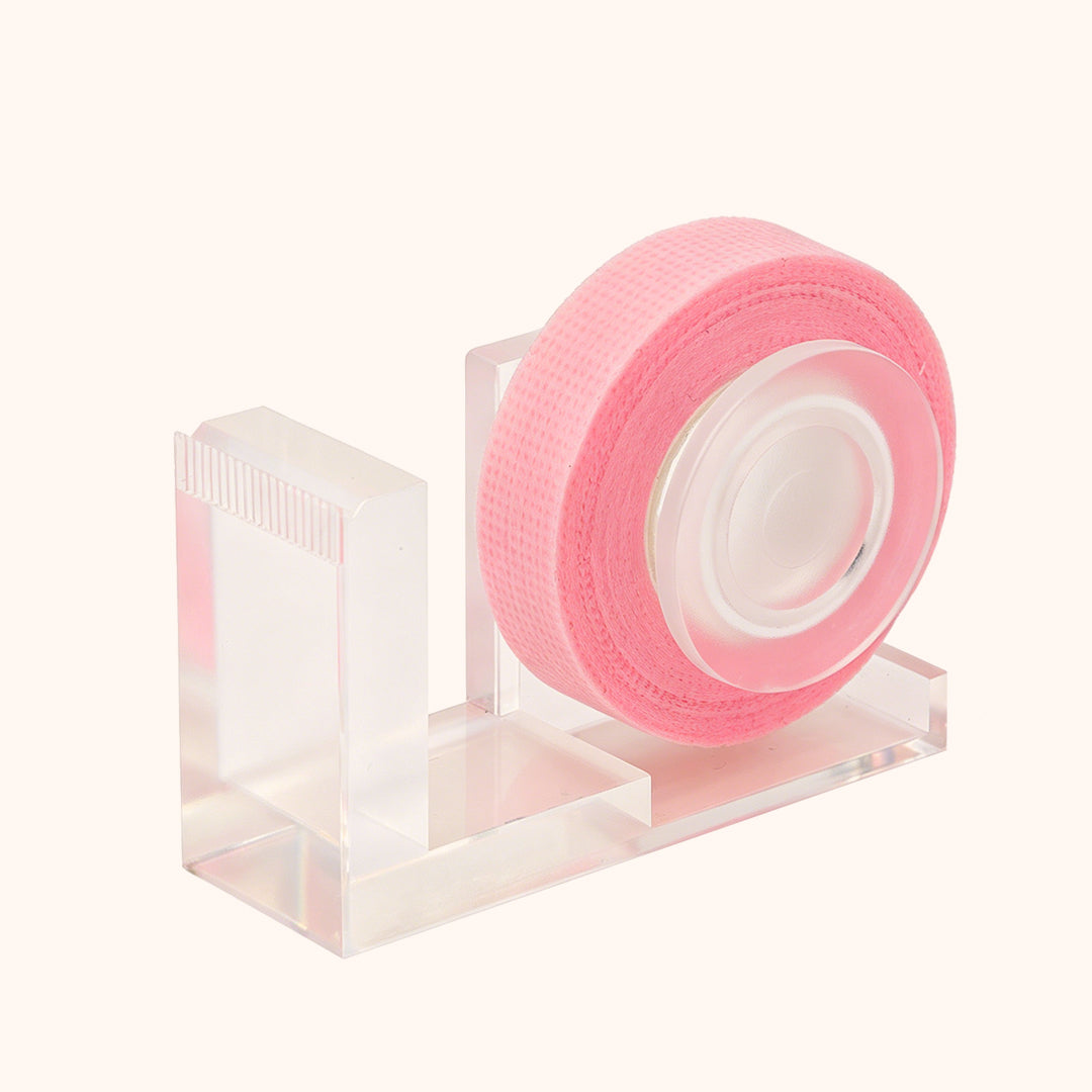 Clear acrylic lash tape dispenser with cutting edge. Stable desktop design for clean even tape cuts, easy roll replacement, keeps lash station neat and efficient.